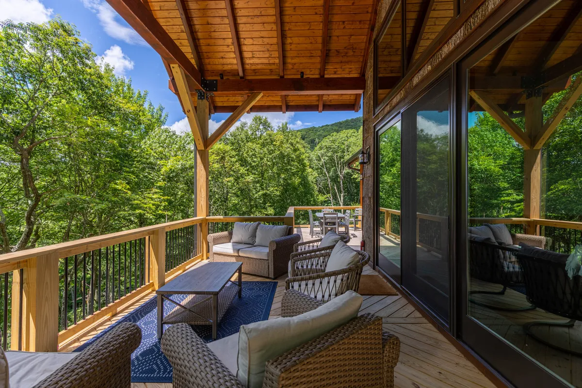 An inviting outdoor seating area with wooden railing overlooks lush greenery and a distant mountain view. It offers a tranquil spot for reading, socializing, or simply soaking up the outdoors, with the mountains evoking the spirit of adventure and exploration.